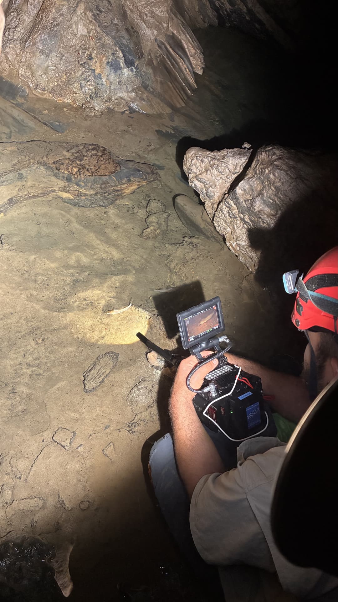 Filmmaker conducting probe work in a shallow cave area
